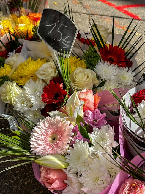 A vibrant floral arrangement featuring a variety of fresh flowers including pink gerbera daisies, white roses, cream carnations, red gerbera daisies, and pink lilies, all artistically arranged and wra
